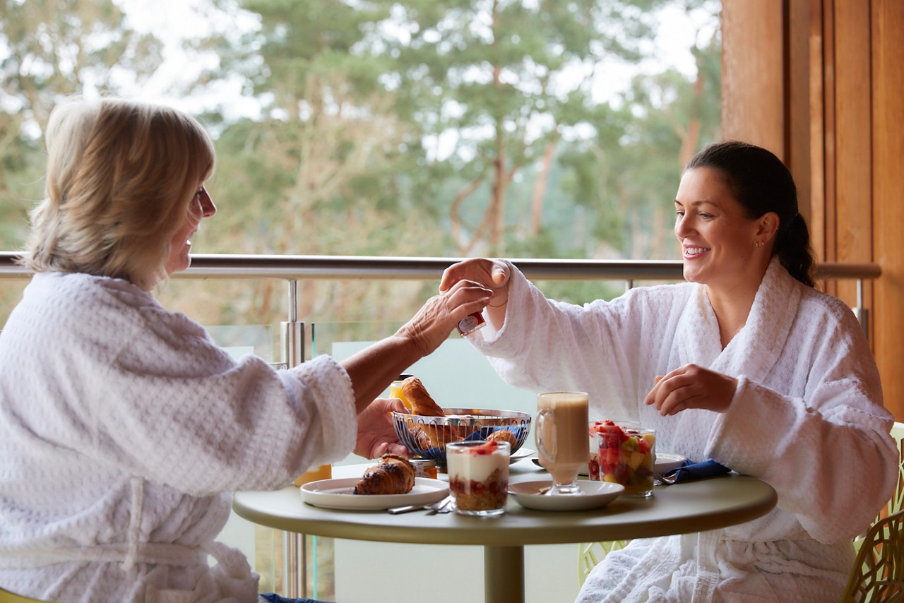 Inside our Spa Apartments with a bed, fresh flowers and views out to the surrounding forest.